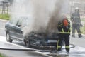 Burning motor vehicle been put out by firemen in protective clot Royalty Free Stock Photo