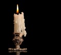 Burning old candle vintage bronze Silver candlestick. Isolated Black Background.