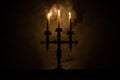 burning old candle vintage wooden candlestick. on dark toned foggy Background.