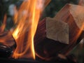 A burning orange bright flame of fire engulfed sections of birch blackened, smoked square logs