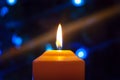 A burning orange candle on a dark background with blue lights - a Christmas New Year`s eve divination mystic esoteric romance lov