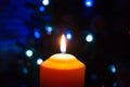 A burning orange candle on a dark background with blue lights - a Christmas New Year`s eve divination mystic esoteric romance lov