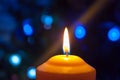 A burning orange candle on a dark background with blue lights - a Christmas New Year`s eve divination mystic esoteric romance lov