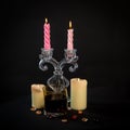 Burning pink and yellow candles. Composition on a dark background with glass stones