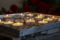 Burning prayer candles inside a catholic church. Lit tea lights. Selective focus Royalty Free Stock Photo