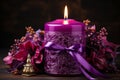Burning purple candle with lilac flowers on a dark background