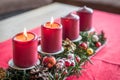 Burning red advent candles with decoration on a wooden table in living room on red fabric cloth at Christmas time, Germany Royalty Free Stock Photo