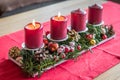 Burning red advent candles with decoration on a wooden table in living room on red fabric cloth at Christmas time, Germany Royalty Free Stock Photo