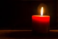 Burning red candle against dark background. Royalty Free Stock Photo