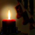 Burning red candle against dark background with silhouettes of stockings Royalty Free Stock Photo