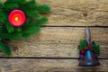 Burning red candle amongst fir branches and Santa bell on an old wood texture. Royalty Free Stock Photo