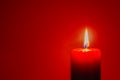Burning red candle on dark red background Royalty Free Stock Photo