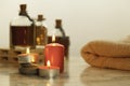 Burning red candles , bath oils and towel on marble table and grey background Royalty Free Stock Photo