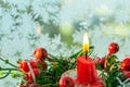 Burning red christmas candle on the background of a frozen window Royalty Free Stock Photo