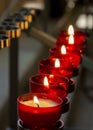 Burning red prayer candles inside a catholic church on a candle rack. Selective focus Royalty Free Stock Photo