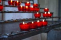 Burning red prayer candles inside a catholic church on a candle rack. Selective focus Royalty Free Stock Photo