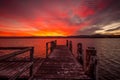 Burning red sunset on the lake with timber jetty