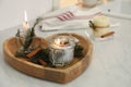 Burning scented conifer candle on white table indoors