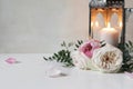 Burning silver Moroccan, Arabic lantern with pink roses flowers and green leaves on white table. Festive still life for