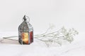 Burning silver vintage Moroccan, Arabic lantern. White gypsophila, babys breath flowers on marble table background Royalty Free Stock Photo