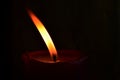 Burning single red candle with dancing flame on the dark background Royalty Free Stock Photo