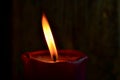 Burning single red candle with dancing flame on the dark background Royalty Free Stock Photo