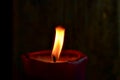 Burning single red candle with dancing flame on the dark background Royalty Free Stock Photo