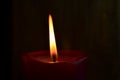 Burning single red candle with dancing flame on the dark background Royalty Free Stock Photo