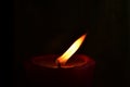 Burning single red candle with dancing flame on the dark background Royalty Free Stock Photo