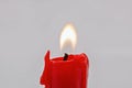 Burning red candle stub closeup on white