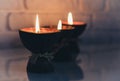 Burning spa aroma candles in coconut shell on a glass white table, cozy home interior