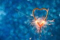 Burning sparkler heart shaped on blue bokeh background.