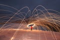 Burning steel wool spreads sparks in a circle. Fire show among high mountains. Winter night landscape