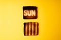 burning sun. yellow poster with two burnt slices of white bread toast with the word Sun on it.