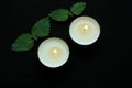 White burning tealight candles on black background. Beauty, SPA treatments, massage therapy and relax concept Royalty Free Stock Photo