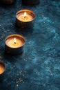 Burning tealights candles on dark blue textured background creating warm light Royalty Free Stock Photo