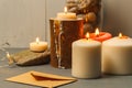 Burning thick white candles in wooden and stone candlesticks and a craft envelope on the table. close-up