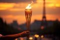 Burning torch in a hand of athlete as a symbol of the Olympic Games in Paris, France, Eiffel tower on background. Olympic games Royalty Free Stock Photo