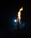 A burning torch at night time with yellow flames. Ancient wooden torch burning on a dark background. A torch burning in the night