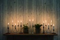 Burning vintage candles on wooden shelf against wooden wall background