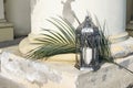 Burning vintage Moroccan, Arabic lantern with date palm leaf in sunlight. Old yellow shabby column. Exotic architecture
