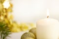 Burning white candle on the background of the New Year Christmas tree, golden balls. on white background. festive mood, Royalty Free Stock Photo