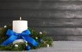 Burning white candle with Christmas decor on table against dark background. Space for text Royalty Free Stock Photo