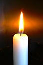 Burning white candle in front of dark background. Royalty Free Stock Photo