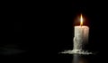 Burning white candle with melted wax trails on black background Royalty Free Stock Photo