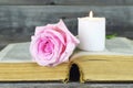 Burning white candle and pink rose on open book Royalty Free Stock Photo