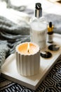 Burning white handmade candle and cosmetic bottles on minimalist tray