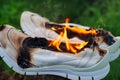 Burning leather sports shoes. Sneakers or gym shoes on fire stand on the Stump.