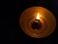 Burning wick of diya with blazing flame in black background