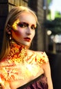 Burning woman golden Halloween face. High Fashion Halloween model woman in golden bright sparkles. Halloween design make